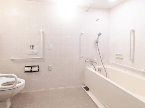 a bathroom with a toilet and a tub and a sink at ART HOTEL Kashima Central in Kamisu