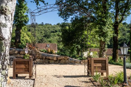 an entrance to a garden with an arch and a stone wall at La Perle de Domme in Sarlat-la-Canéda