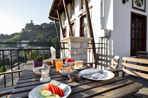 a wooden table with food and drinks on a balcony at Kalemi Twin Boutique Hotel in Gjirokastër