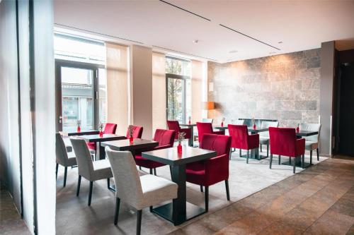 a dining room with tables and red chairs at ATLANTIC Hotel Lübeck in Lübeck