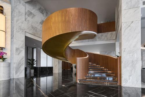 a spiral staircase in a lobby with a wooden stair case at Arula Mianyang Jianshan Hotel-绵阳见山檀程酒店 in Mianyang