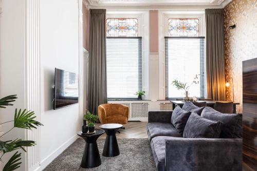 a living room with a couch and two windows at Stylish city center villa tilburg in Tilburg