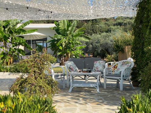 a patio with three chairs and a table in a garden at Azzure Heaven in Loutrá Elevtherón