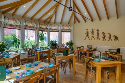 a restaurant with wooden tables and chairs and windows at Darwins Townhouse in Shrewsbury