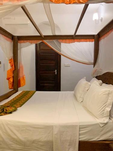 a bedroom with a bed with white sheets and pillows at Princess Salme Inn in Zanzibar City