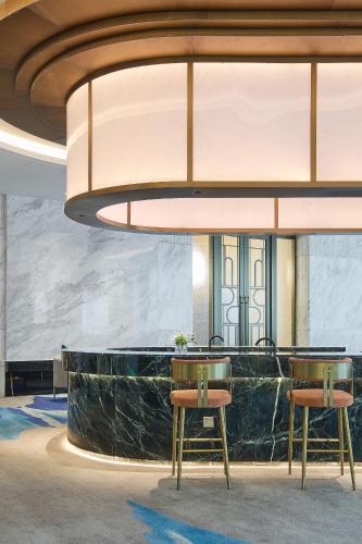 a lobby with a bar with two chairs and a largeandelier at Arula Mianyang Jianshan Hotel-绵阳见山檀程酒店 in Mianyang