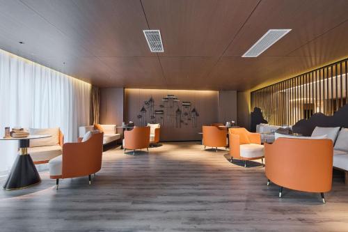 a waiting room with orange chairs and tables at Arula Mianyang Jianshan Hotel-绵阳见山檀程酒店 in Mianyang