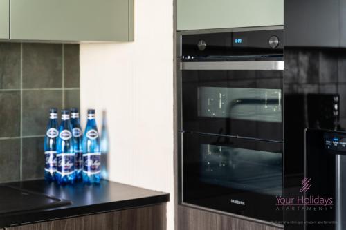 Un grupo de botellas de agua en un mostrador junto a un horno. en Your Holidays Aquamarina Prima 60, en Międzyzdroje
