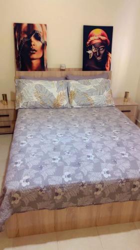 a bed in a bedroom with two posters on the wall at Hõte ibra in Tangier