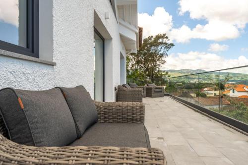 a patio with wicker furniture on a balcony at Ápice - by Azores Green Villas in São Vicente Ferreira