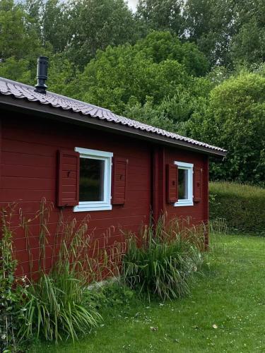 a red house with two windows in the grass at Chalet en bord d'étang in Longpré-les-Corps-Saints