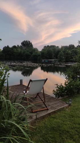 a chair sitting on a dock next to a lake at Chalet en bord d'étang in Longpré-les-Corps-Saints