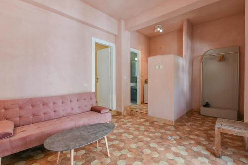 Casa al Castelllo - Traditional home in Parga في بارغا: غرفة معيشة مع أريكة وردية وطاولة