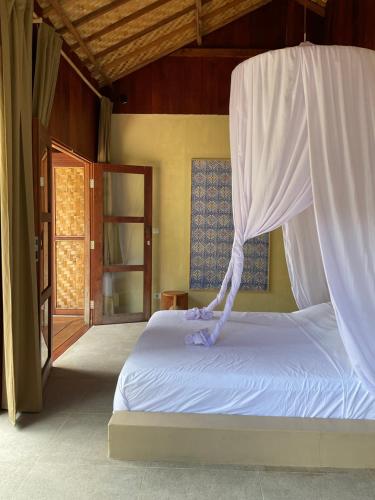 a bedroom with a bed with a mosquito net at Tumbuh Oasis in Letman