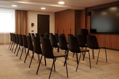 a row of chairs in a room with a screen at AIRINN Vilnius Airport Hotel RENOVATED 2025 in Vilnius