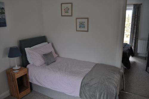 a bedroom with a bed and a night stand with a lamp at Morley's in Stithians