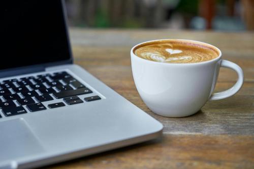 a cup of coffee next to a laptop computer at Garner Hotel Maastricht by IHG in Maastricht