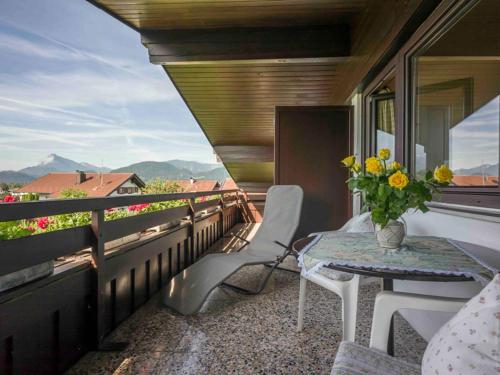 a balcony with a table and chairs and a vase of flowers at Tirol Appartements Schwaiger in Niederndorf