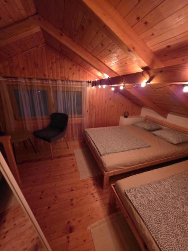 a room with two beds and a chair in a cabin at Kuća za odmor Marinano in Slavonski Brod