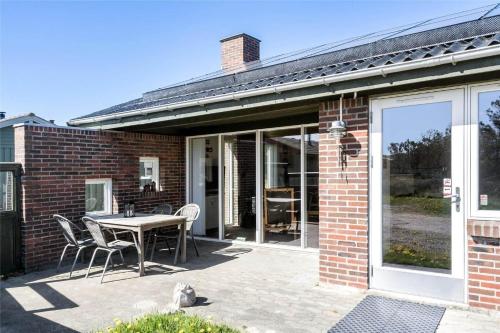 a brick house with a table and chairs on a patio at 991-Thisted-Liusborg-Sti-23 in Torsted