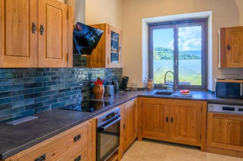 une cuisine avec des placards en bois et une grande fenêtre dans l'établissement Le Joly Mont, à Saint-Gervais-les-Bains