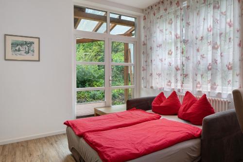 a bedroom with a bed with red pillows and a window at Jogis Ferienwohnungen in Freiburg im Breisgau