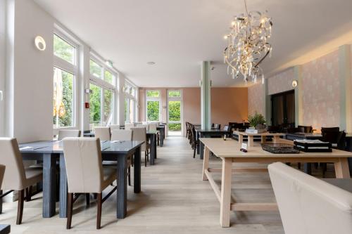 a dining room with tables and chairs and a chandelier at Garner Hotel Oberhausen in Oberhausen