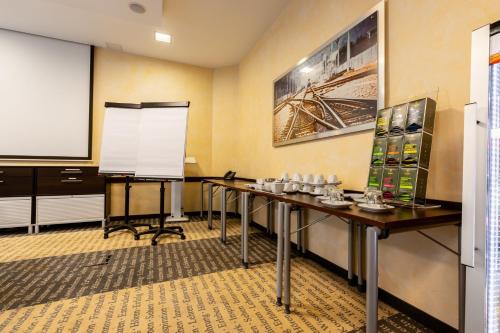 a conference room with two tables and a projection screen at Garner Hotel Oberhausen in Oberhausen