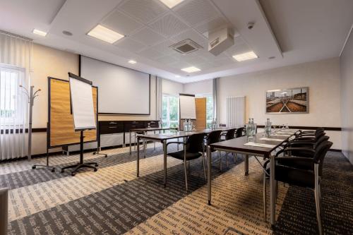 a conference room with tables and chairs and a projection screen at Garner Hotel Oberhausen in Oberhausen