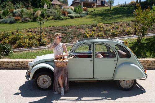 a woman standing next to an old car at La Perle de Domme in Sarlat-la-Canéda
