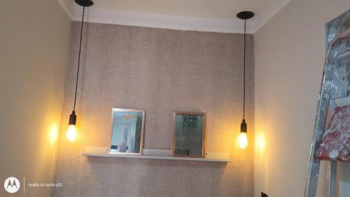 two lights hanging from a wall with a shelf at Studio Romantico Privativo in Volta Redonda