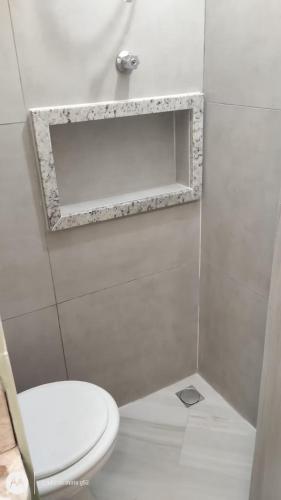 a bathroom with a white toilet and a mirror at Studio Romantico Privativo in Volta Redonda