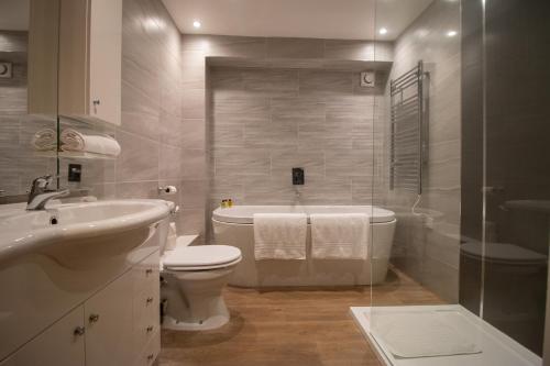 a bathroom with a tub and a toilet and a sink at Dovestays in Laxton