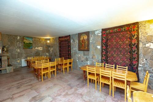 a dining room with wooden tables and a stone wall at Valodia's Cottage in Vardzia