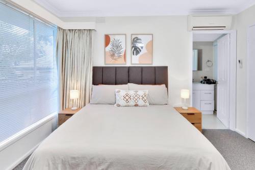 a bedroom with a large white bed and a window at Sunbury large family home pet friendly airport in Sunbury