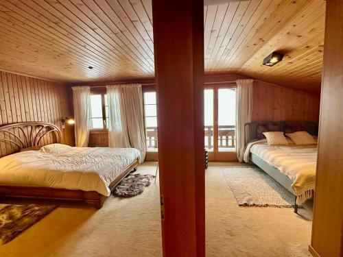 a bedroom with two beds in a room with windows at Chalet Bliss with Spectacular Views in Chateau-d'Oex