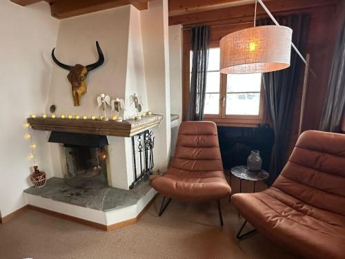 a living room with a fireplace and two chairs at Chalet Bliss with Spectacular Views in Chateau-d'Oex