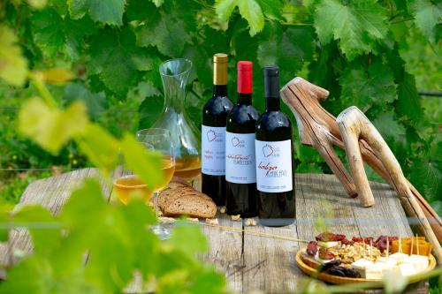 three bottles of wine and a plate of food on a table at Valodia's Cottage in Vardzia