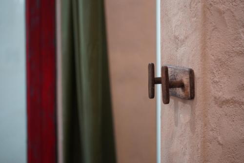 a wooden door knocker on the side of a wall at Dechiu in Hoi An