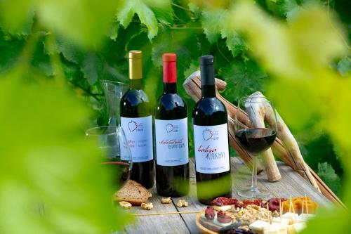 three bottles of wine sitting on a wooden table at Valodia's Cottage in Vardzia