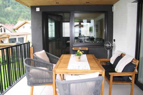a patio with a wooden table and chairs on a balcony at Apart Bieles NEU - Bergoase mit privater Outdoor-Sauna & Massagepraxis in Kauns