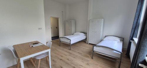 a room with two beds and a table and a desk at GASTEM UG in Berlin