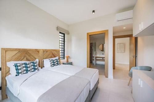 a bedroom with a large white bed and a bathroom at Eko Savannah by MJ Holidays in Tamarin