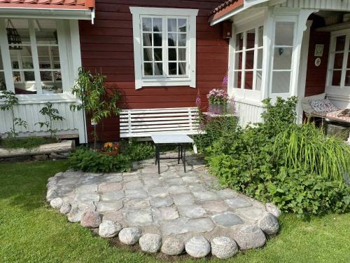a house with a bench in the front yard at Cozy guest house in the countryside in Håltebyn