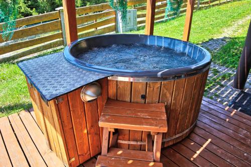 a wooden tub sitting on a deck with a wooden stool at Solna Chata-dom na wyłączność Grota solna, balia, sauna, basen in Rajcza