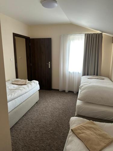 a hotel room with two beds and a window at Penzión Dolina in Vinné