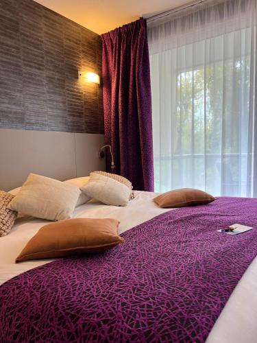 a large purple bed with pillows and a window at Hotel & Spa Marina d'Adelphia in Aix-les-Bains