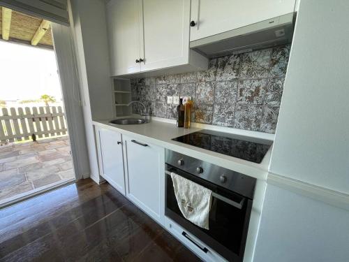 a kitchen with white cabinets and a stove top oven at Aphrodite Beachfront Resort Official in Ghaziveran