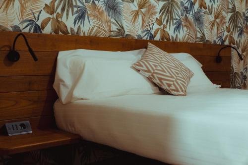 a bed with white sheets and pillows in a room at Fiore di Langa - Residence in Monforte d'Alba in Monforte dʼAlba