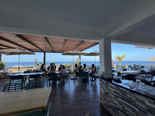 people sitting at tables in a restaurant with a view of the ocean at Hotel Por Do Sol in Tarrafal